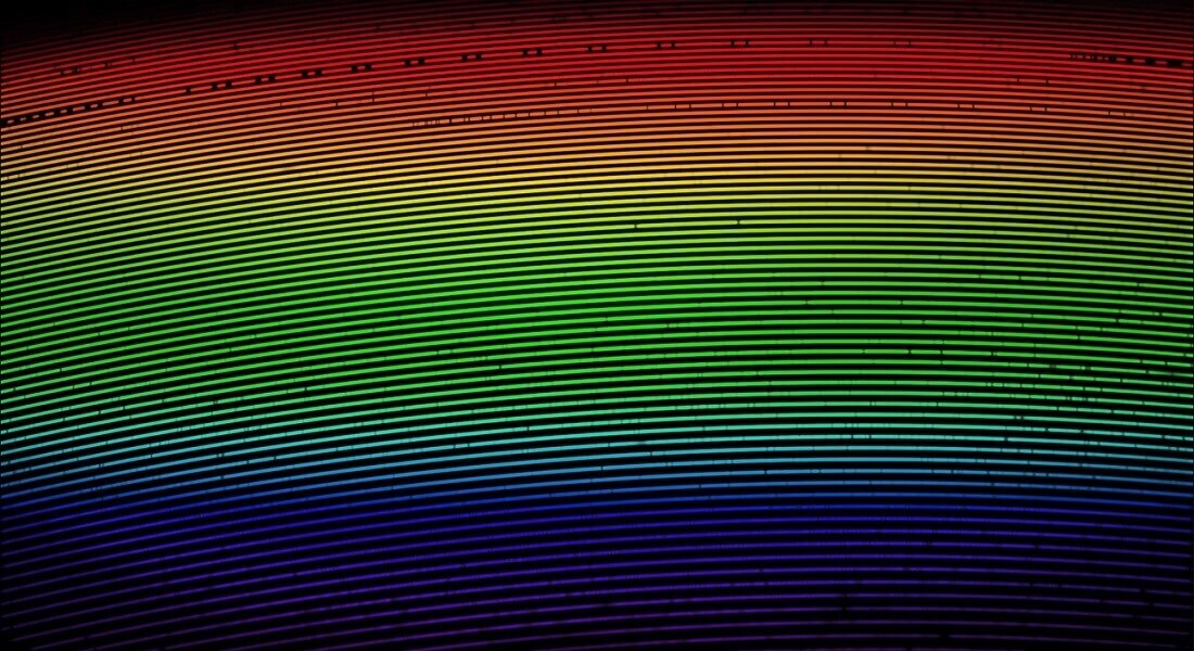 A spectrum of the Sun from the Lowell Observatory Solar Telescope, color-coded to approximate the color of light seen by human eyes. The vertical dark bands are absorption features of molecules in the atmosphere of the Sun. Dr. Llama uses the position of these bands to measure the solar radial velocity. (Images provided by Lowell Observatory)
